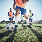 A group of diverse people playing soccer together on a field.