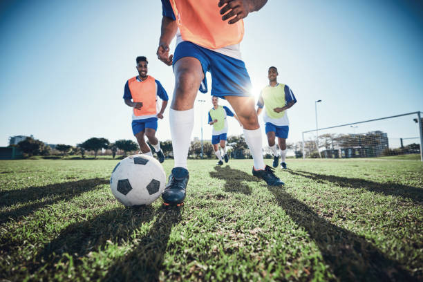 A group of diverse people playing soccer together on a field.