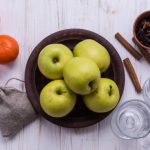 Apple cider vinegar gummies on a wooden table with apples in the background.